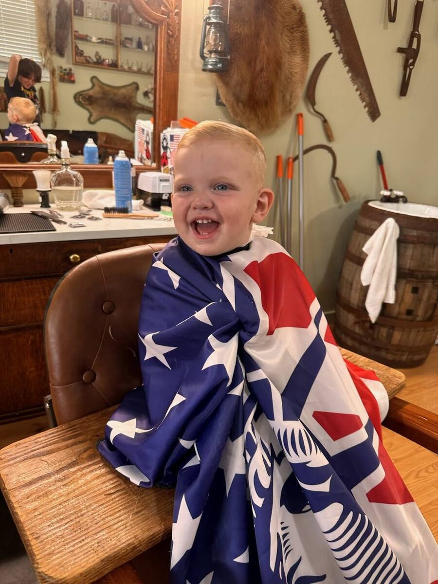 Smiling young boy with short haircut in American flag cape
